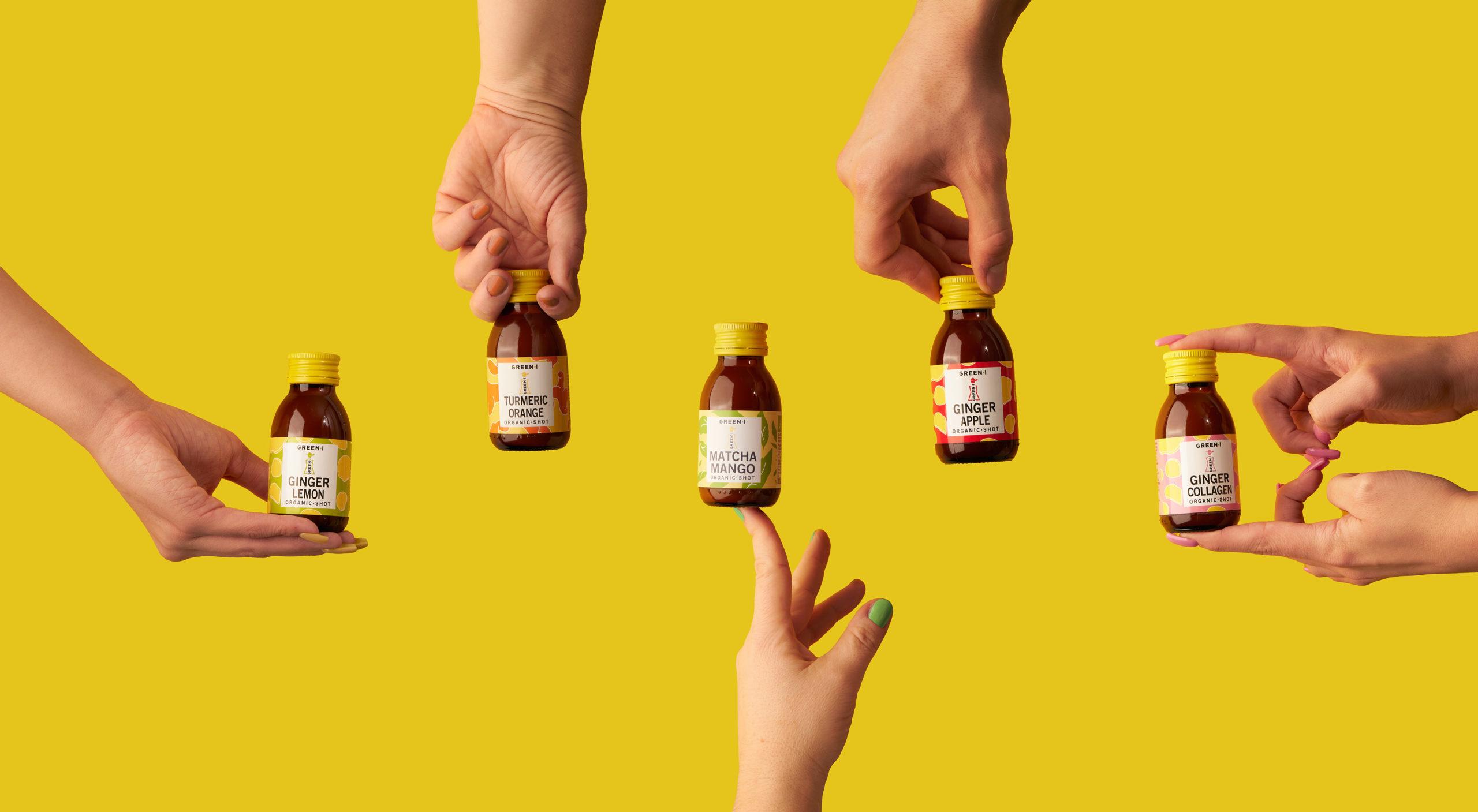 Hands and bottles of fruit juices on yellow background